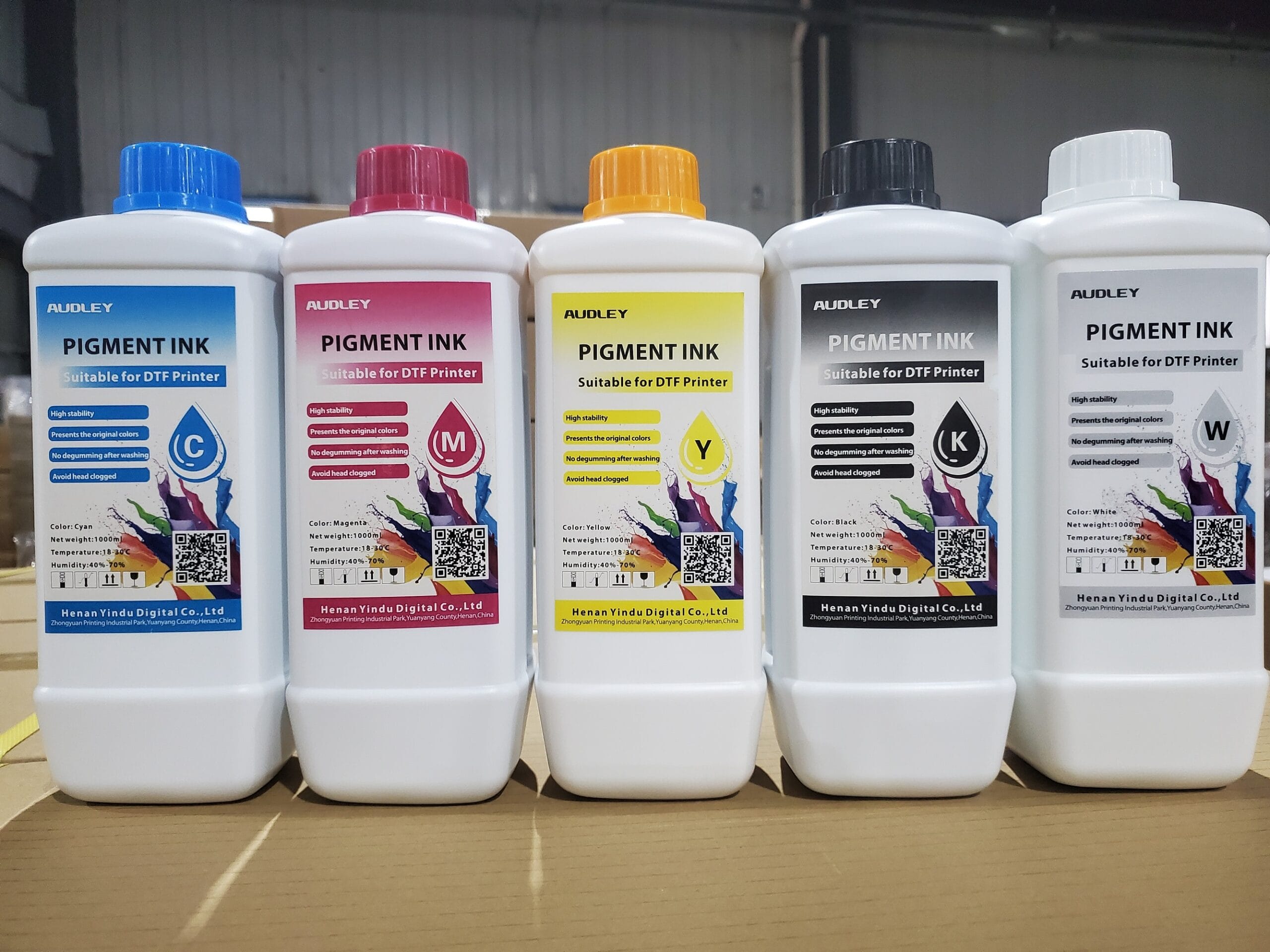 Les 5 bouteilles d'encre DTF Audley (Cyan, Magenta, Jaune, Noir et Blanc) alignées.