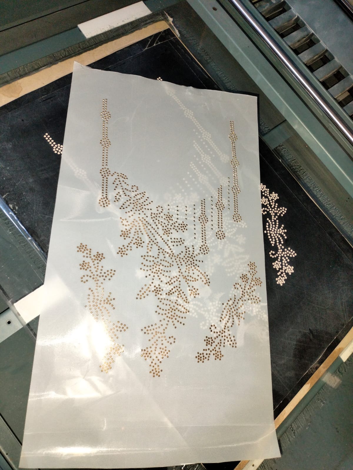 Film de transfert avec motif en strass positionné sur la table de travail de la machine automatique DISEN